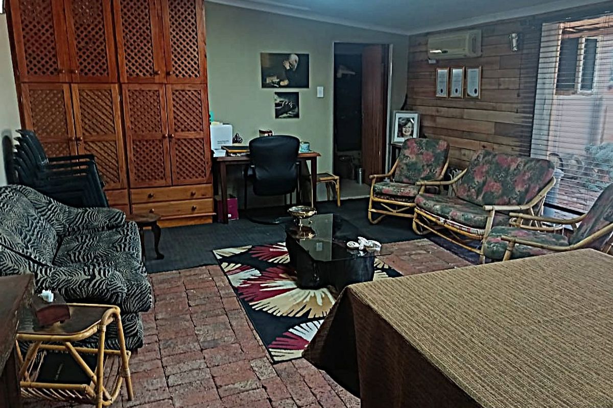 A living room featuring rustic brick flooring, wood-paneled walls, built-in cabinetry, and a split-system air conditioner.