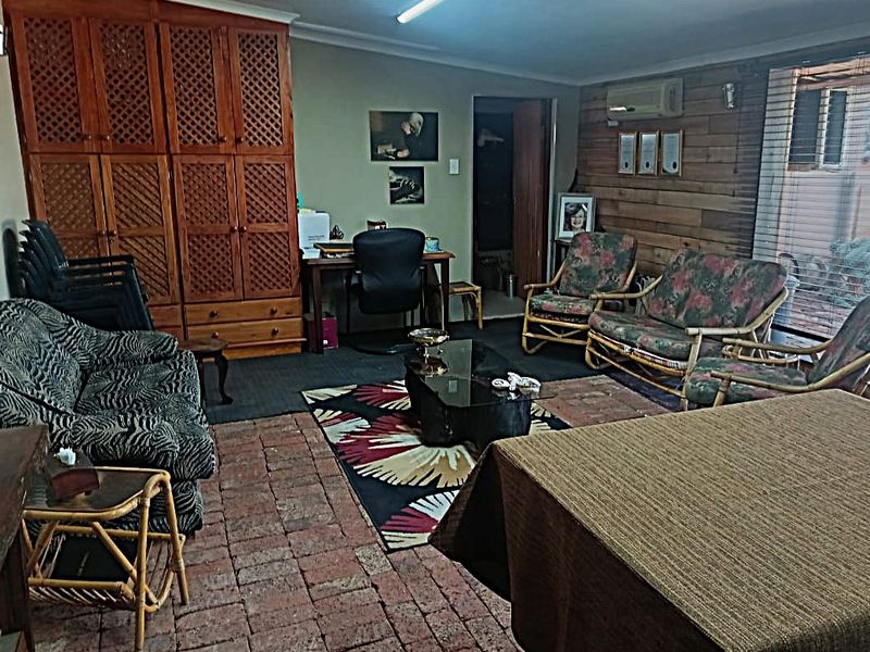 A living room featuring rustic brick flooring, wood-paneled walls, built-in cabinetry, and a split-system air conditioner.