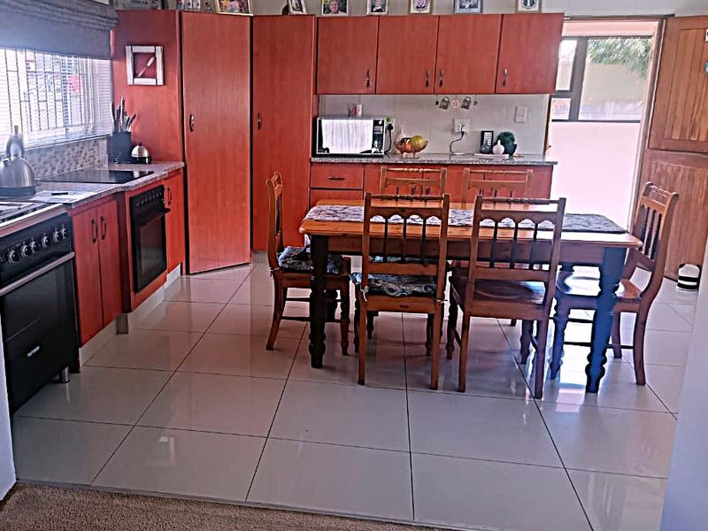 Open-plan kitchen and dining area featuring wooden cabinetry, tiled flooring, and integrated appliances, providing a functional space for cooking and family meals.