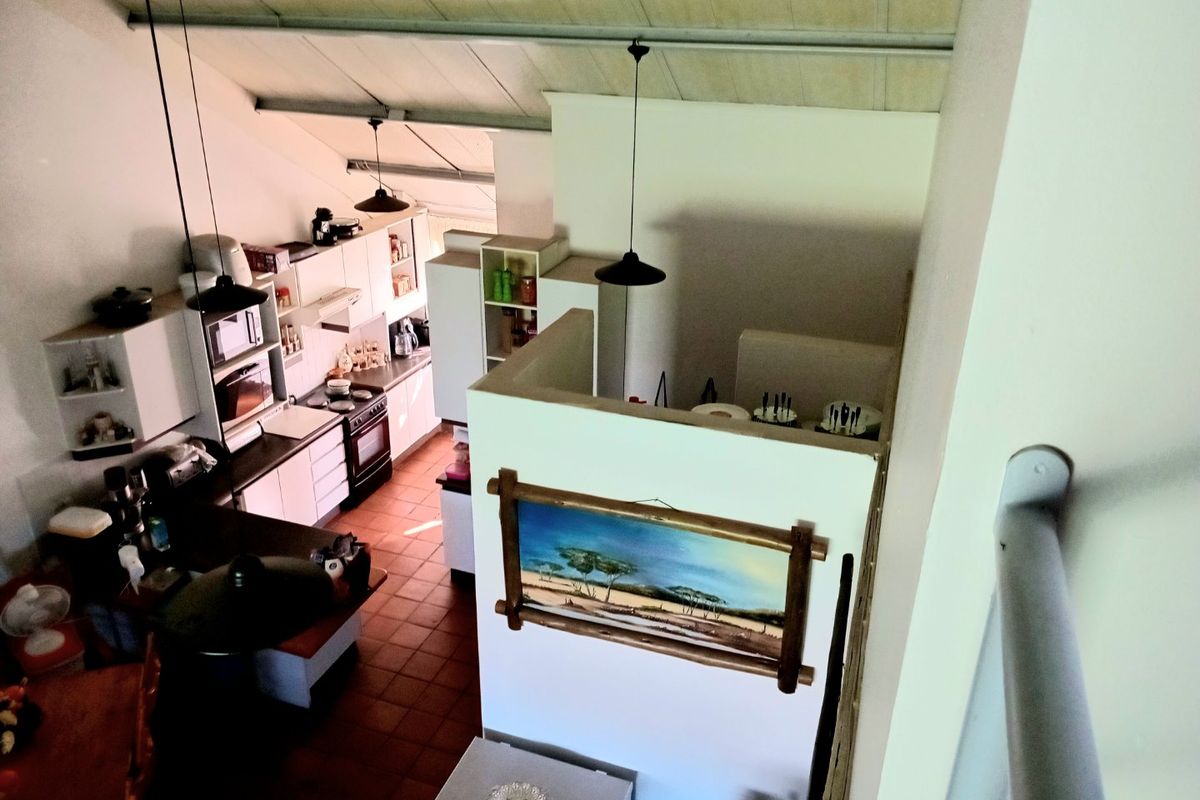High-angle view of a kitchen featuring built-in cabinetry, a stove, and tiled flooring under a vaulted ceiling.