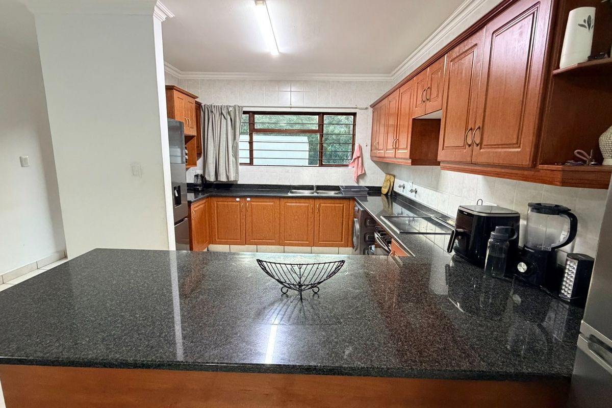 A functional kitchen featuring wooden cabinetry, granite countertops, a double sink, and tiled backsplash, offering a classic layout with ample storage space.