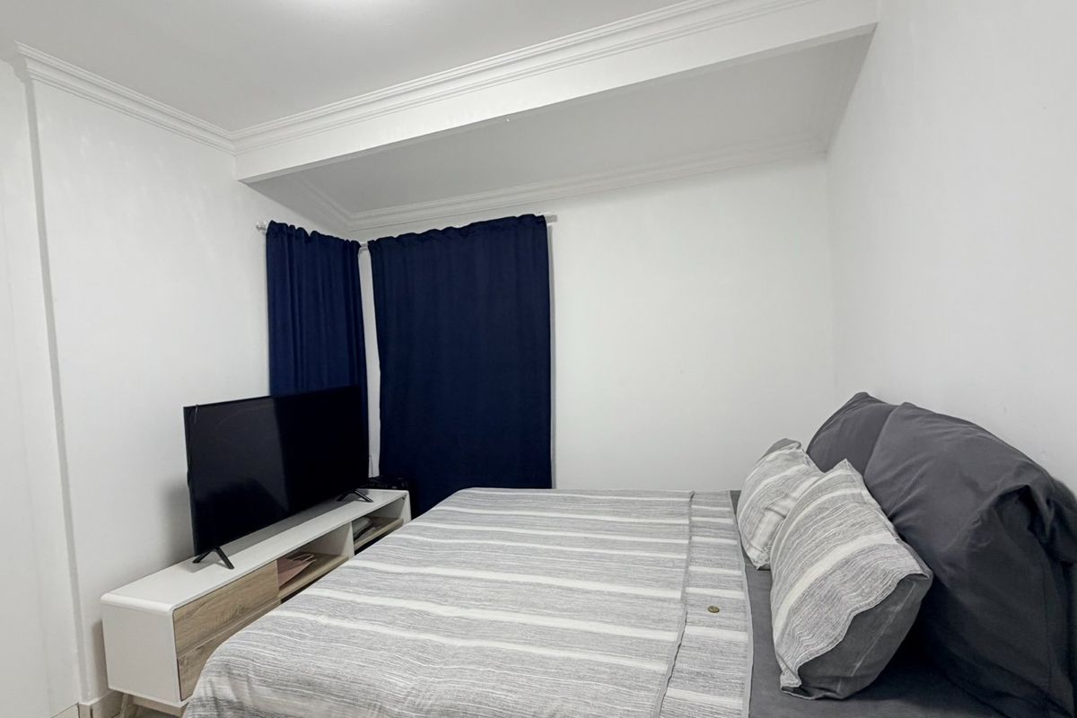 A clean and simple bedroom featuring white walls and decorative crown molding.