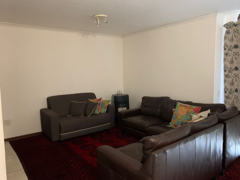 A living room area featuring tiled flooring, coving, and a built-in gas heater, providing a functional space for relaxation.