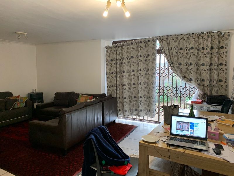 Open-plan living area featuring tiled flooring and a sliding door with a security gate leading to the exterior.