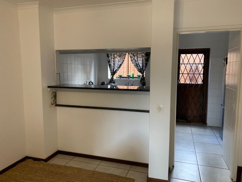 A functional kitchen area featuring a breakfast bar, tiled flooring, and a direct view into the adjacent utility space with a secure rear door.