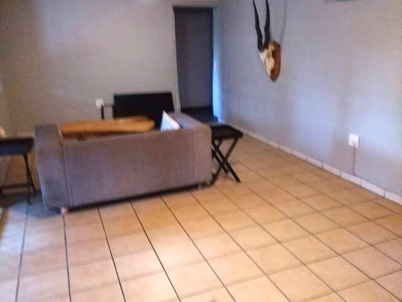 A living room featuring ceramic floor tiles, a coved ceiling, and a wall-mounted split-system air conditioning unit.