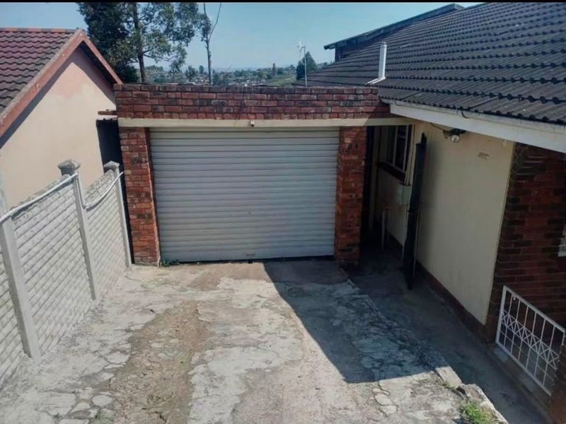 Exterior view of a single garage with a roller door, featuring a concrete driveway and brick construction.