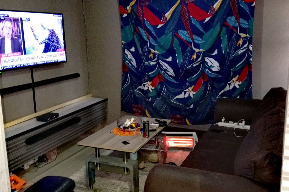 A compact living room featuring tiled flooring and cove cornicing, currently utilized as a casual media space.