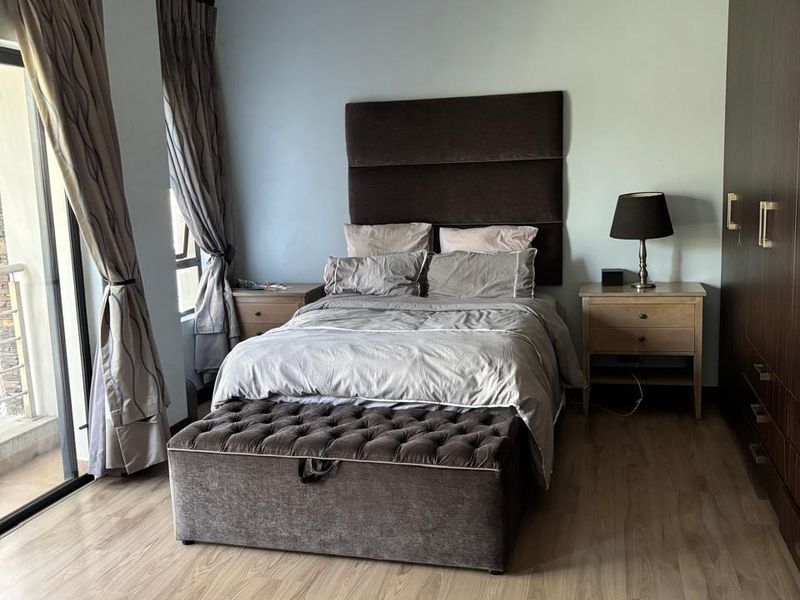 A well-maintained bedroom featuring light wood-look laminate flooring, built-in cabinetry, and a sliding glass door providing access to an outdoor area.