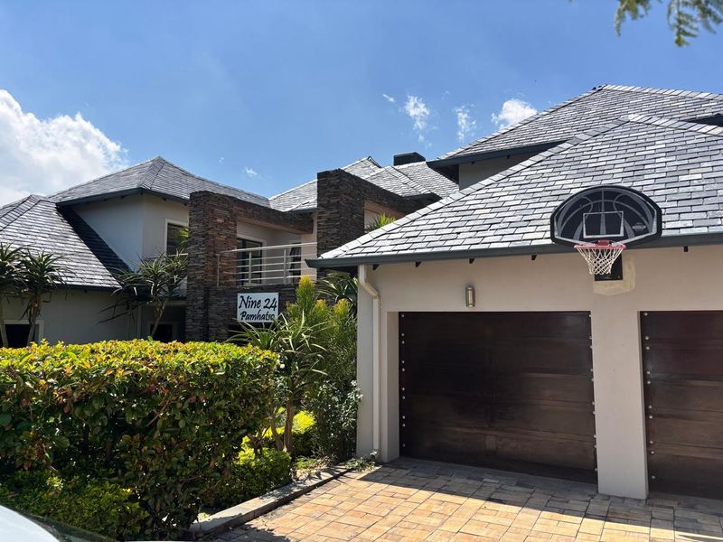 Front elevation of a modern residence featuring a slate roof, stone-clad accents, a double garage, and a paved driveway.