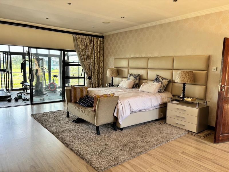 Spacious bedroom featuring laminate flooring, recessed lighting, and large sliding glass doors providing access to an adjacent balcony area.
