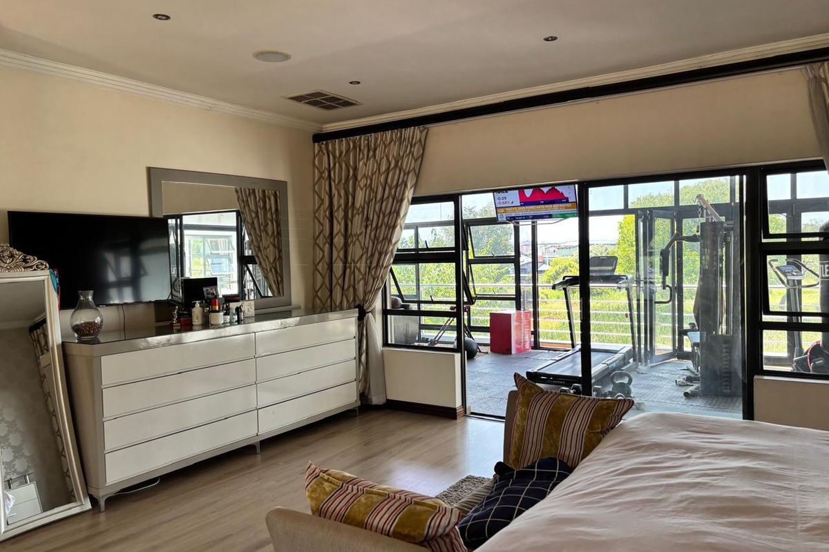 Spacious bedroom featuring laminate flooring, recessed lighting, and large sliding glass doors that open onto an adjacent balcony area.