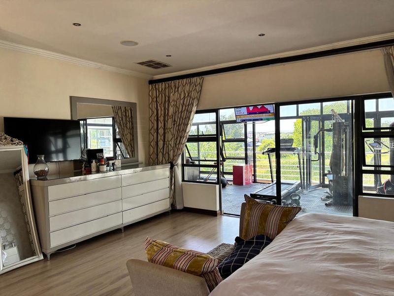 Spacious bedroom featuring laminate flooring, recessed lighting, and large sliding glass doors that open onto an adjacent balcony area.