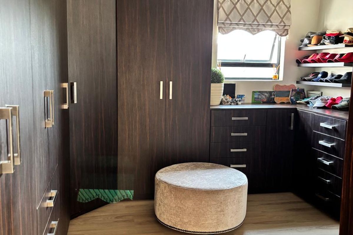 A well-appointed dressing room or bedroom featuring extensive dark wood built-in cabinetry, laminate flooring, and recessed lighting.