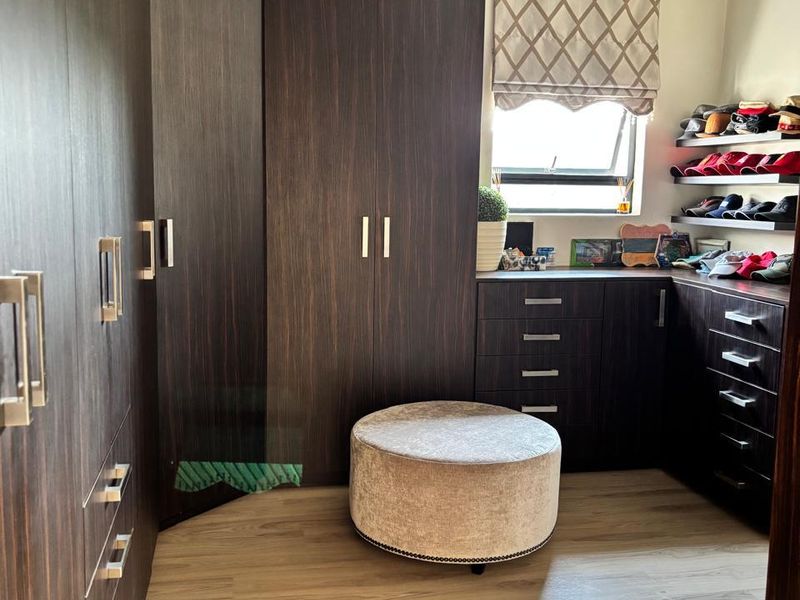 A well-appointed dressing room or bedroom featuring extensive dark wood built-in cabinetry, laminate flooring, and recessed lighting.