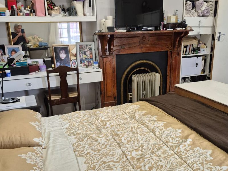 Bedroom featuring a classic wooden fireplace mantel with a cast iron insert and built-in shelving units for storage.