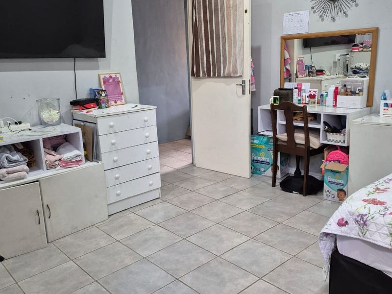 A bedroom featuring neutral wall paint and tiled flooring, providing a functional space with direct access to an adjoining room.