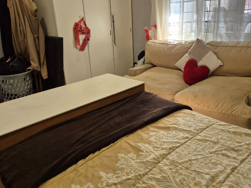 A bedroom featuring a window with security bars, providing natural light and functional space.