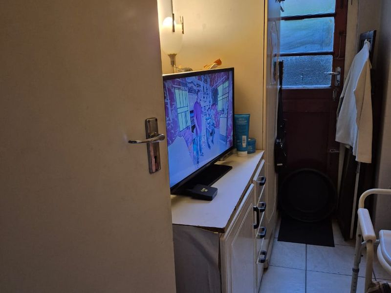 A narrow hallway featuring tiled flooring, built-in cabinetry, and an external door providing access to the exterior.