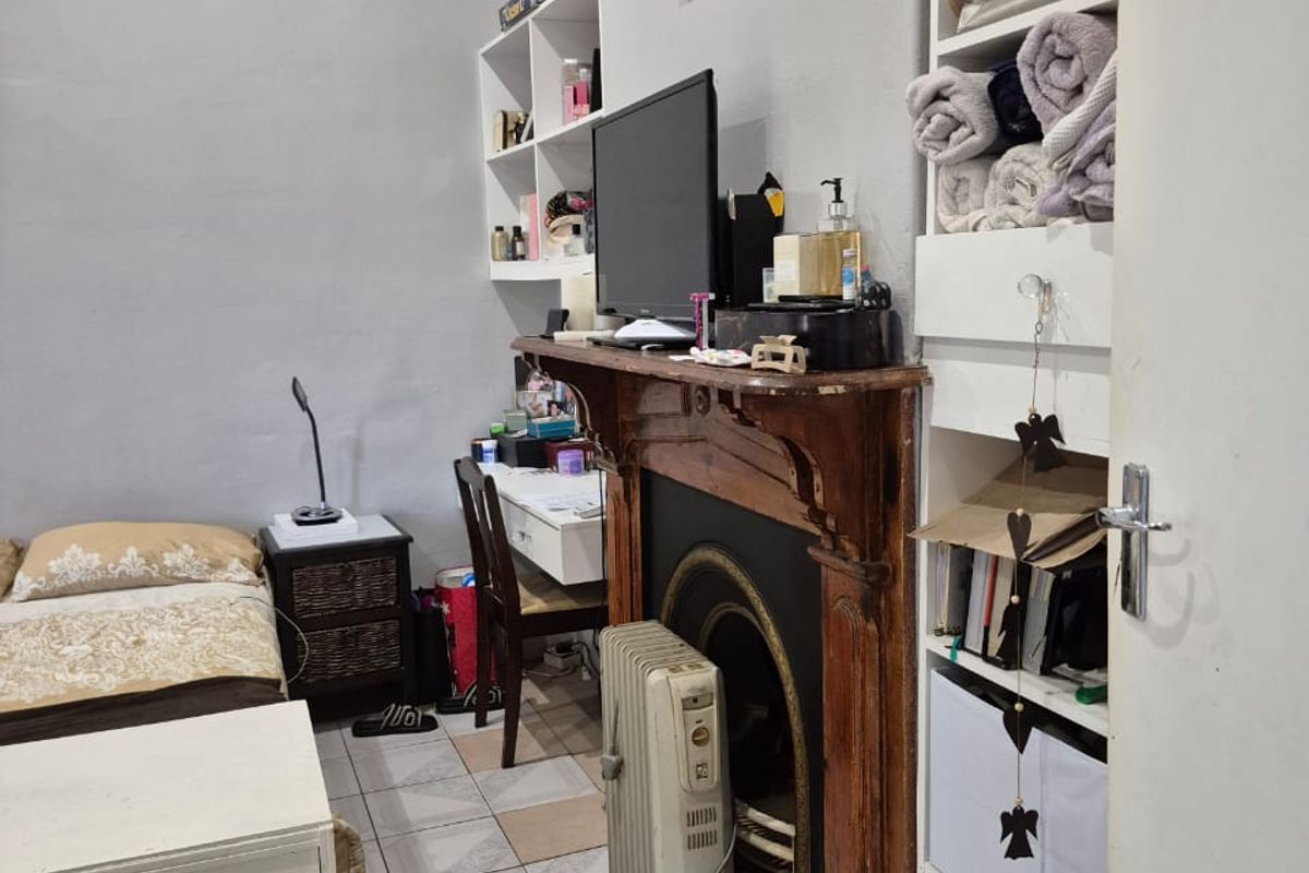 Bedroom featuring an ornate timber fireplace mantel with cast iron insert, built-in shelving, and tiled flooring.
