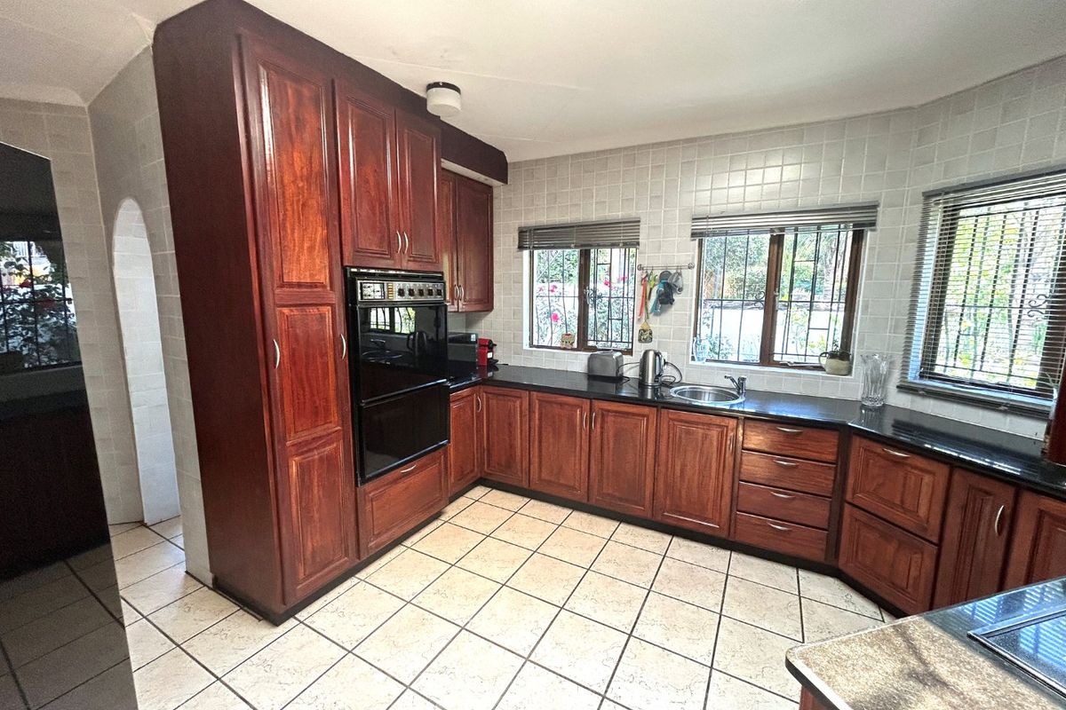 A functional kitchen featuring dark wood cabinetry, black granite countertops, a built-in double oven, and tiled flooring with a classic layout.