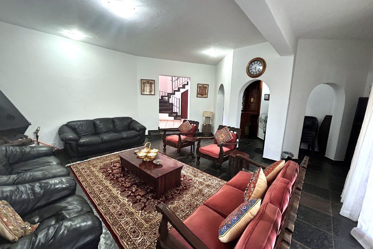 Spacious living room featuring stone tile flooring, arched architectural doorways, and recessed lighting, providing a traditional layout with access to adjacent areas.