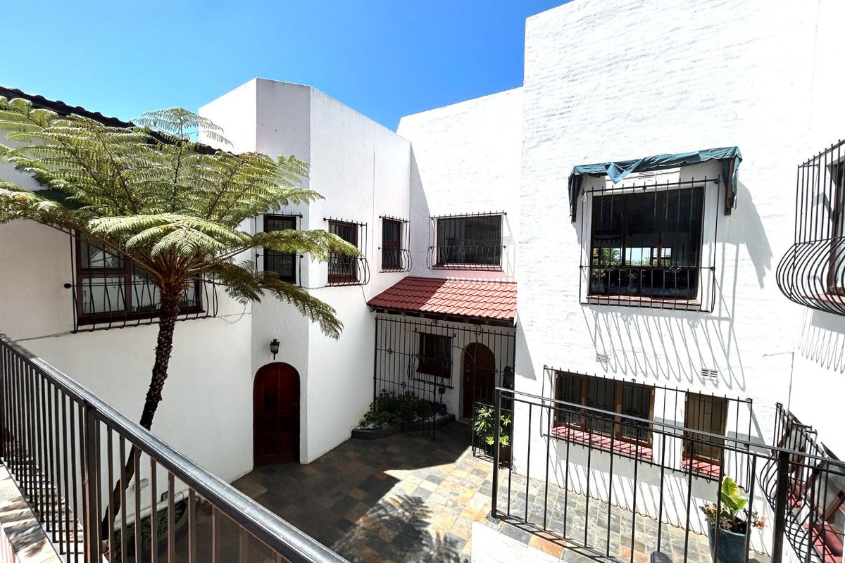 A private rear courtyard featuring tiled flooring, security bars on windows, and arched wooden entry doors, providing a secure outdoor space.