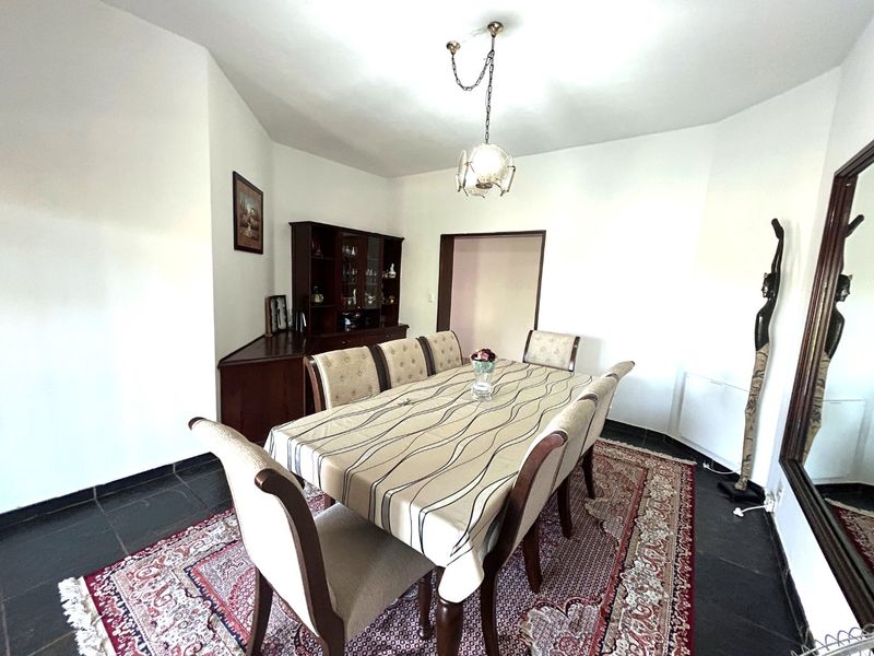 A dining room featuring dark tiled flooring and a central pendant light fixture, providing a functional space for family meals.