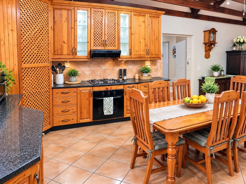 Open-plan kitchen and dining area featuring traditional timber cabinetry, granite countertops, gas cooktop, and exposed timber ceiling beams.