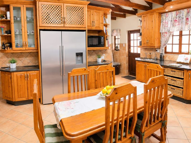 Spacious open-plan kitchen and dining area featuring warm wooden cabinetry, granite countertops, and exposed timber ceiling beams.