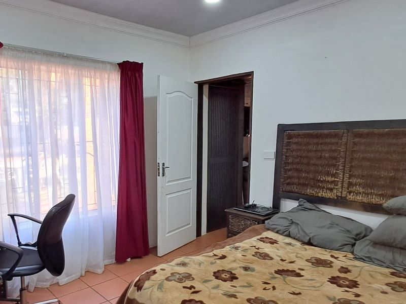 A functional bedroom featuring tiled flooring, coved ceiling details, and a standard panel door, offering a comfortable and practical living space.