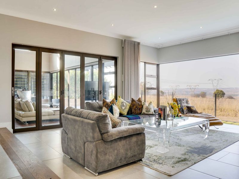 Spacious living room featuring large aluminium sliding doors, expansive corner windows, and modern recessed lighting, offering seamless indoor-outdoor flow and natural light.
