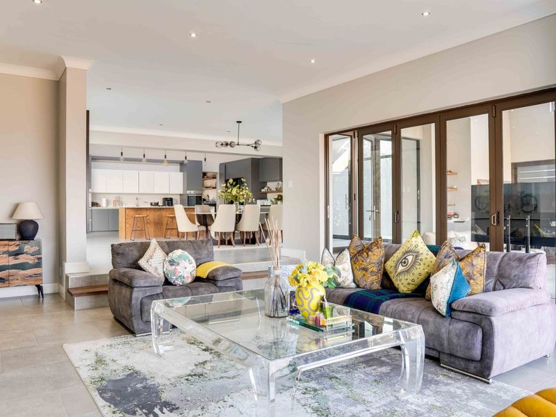 Spacious open-plan living and dining area featuring modern tiled floors, recessed lighting, and seamless flow to the outdoor patio through large bi-fold doors.