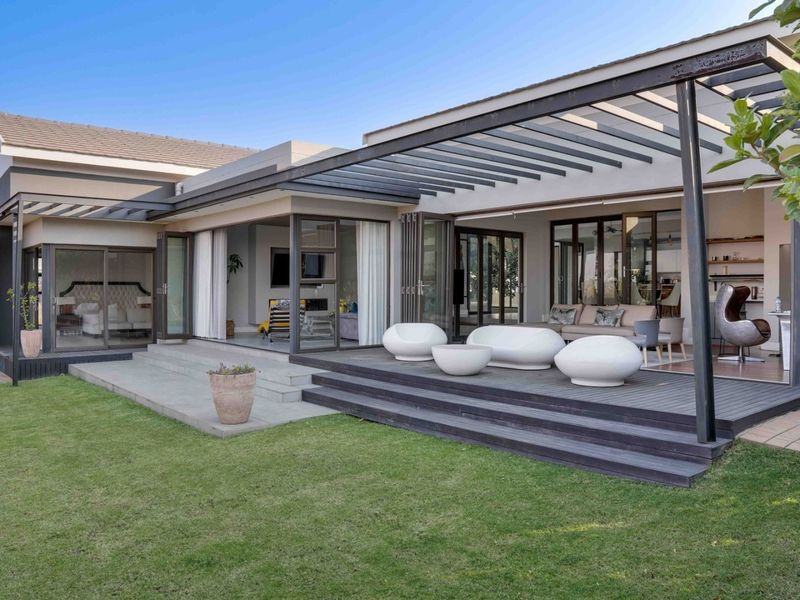 Spacious covered patio featuring timber decking, a modern pergola, and large stacking glass doors that provide seamless indoor-outdoor flow to the garden.