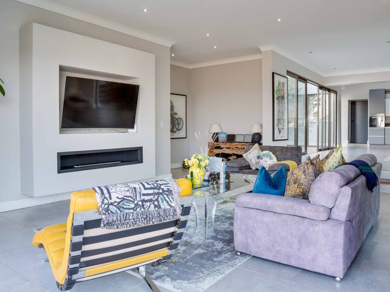 Spacious open-plan living area featuring a modern built-in media wall with a recessed fireplace, tiled flooring, and large sliding doors leading to the exterior.