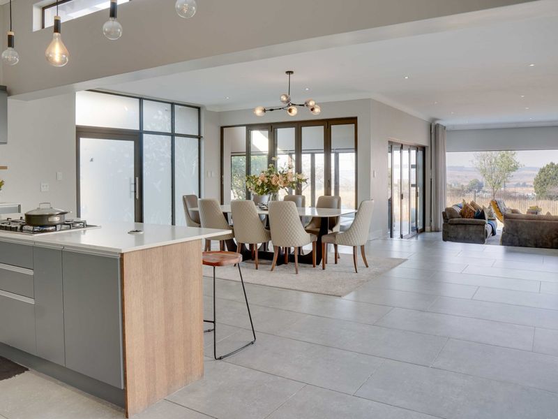Spacious open-plan living area featuring a modern kitchen with island, dining space, and seamless flow to outdoor views through large sliding glass doors.