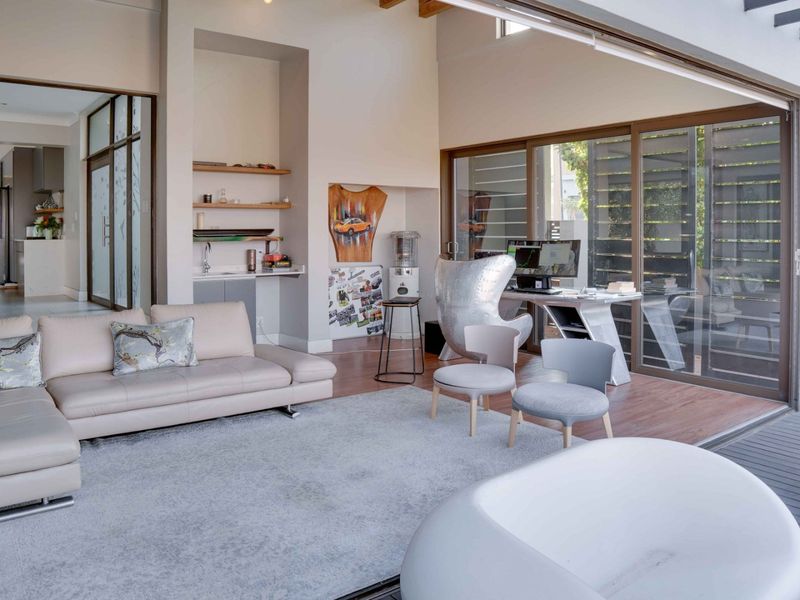 Spacious open-plan living area featuring high ceilings with exposed timber beams, built-in wet bar, and large sliding glass doors opening to the outdoor deck.
