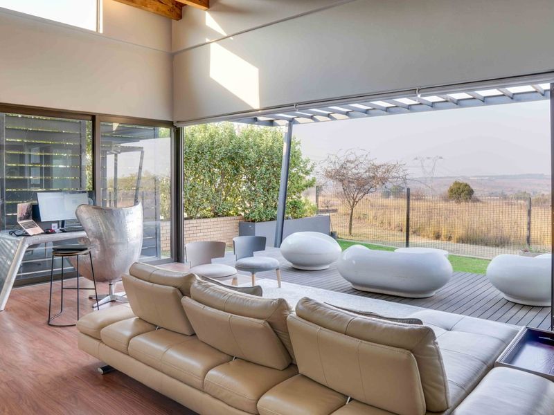 Spacious open-plan living area featuring high ceilings with exposed beams, large sliding glass doors, and seamless transition to an outdoor timber deck.