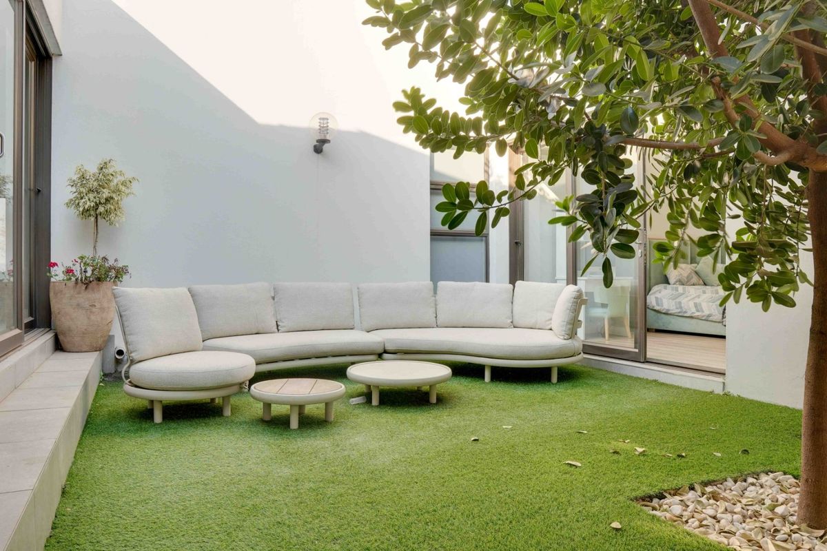 A well-maintained rear courtyard featuring artificial turf, stone landscaping, and seamless access to the interior through large sliding glass doors.