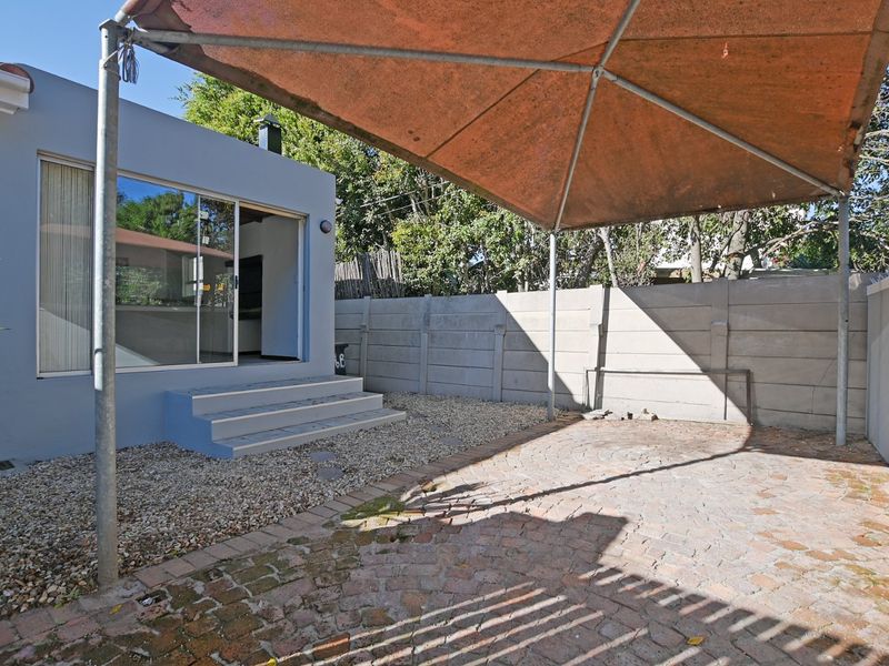 A private outdoor patio area featuring paved flooring, a gravel garden section, and a sliding door entrance to the main dwelling.