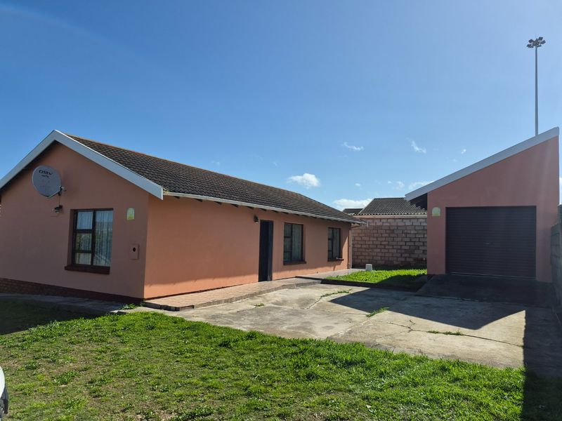 Front view of a single-story house featuring a tiled roof, concrete driveway, and an attached single garage with a roll-up door.
