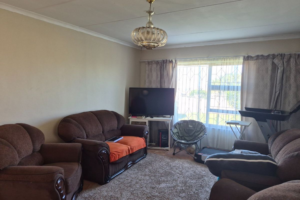 A living room featuring tiled flooring, coving, and a security gate on the window, providing a functional space for relaxation.
