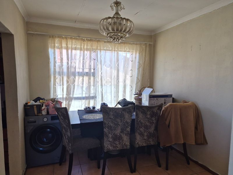 Dining area featuring tiled flooring and a decorative chandelier, showing signs of wear on the ceiling.