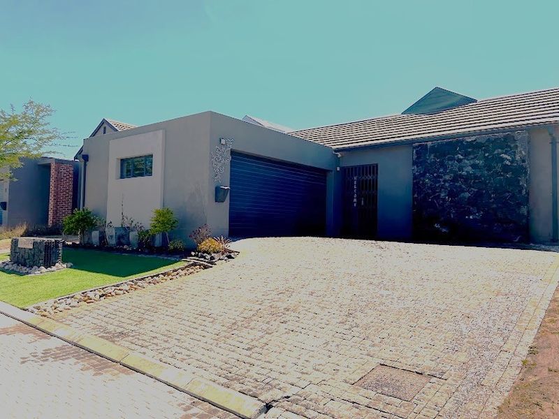 Modern front elevation featuring a paved driveway, integrated garage, and a distinctive stone-clad feature wall.