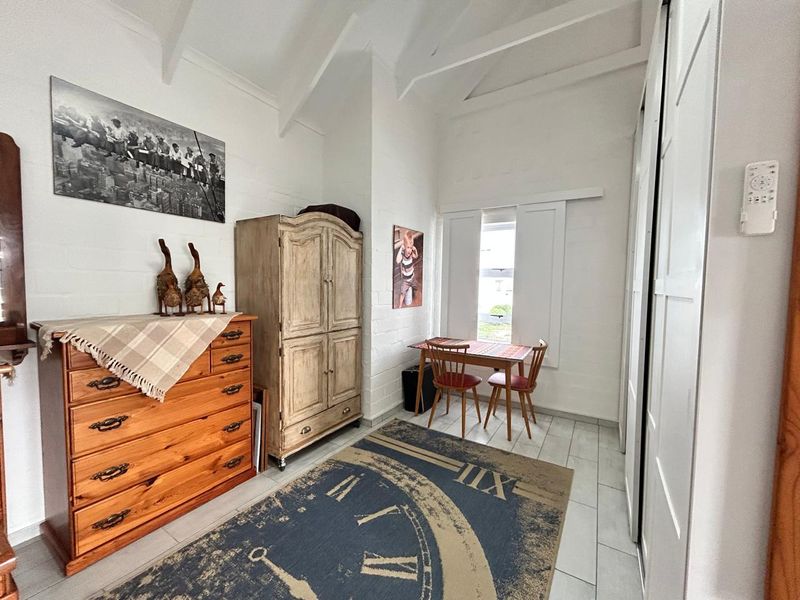 A bedroom featuring vaulted ceilings, tiled flooring, and built-in sliding door wardrobes, offering a bright and functional living space.
