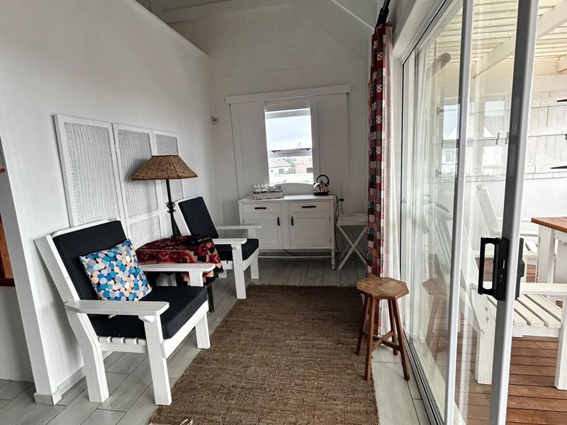 A bright, enclosed patio area featuring vaulted ceilings with exposed rafters, tiled flooring, and large sliding glass doors providing access to the outdoor space.