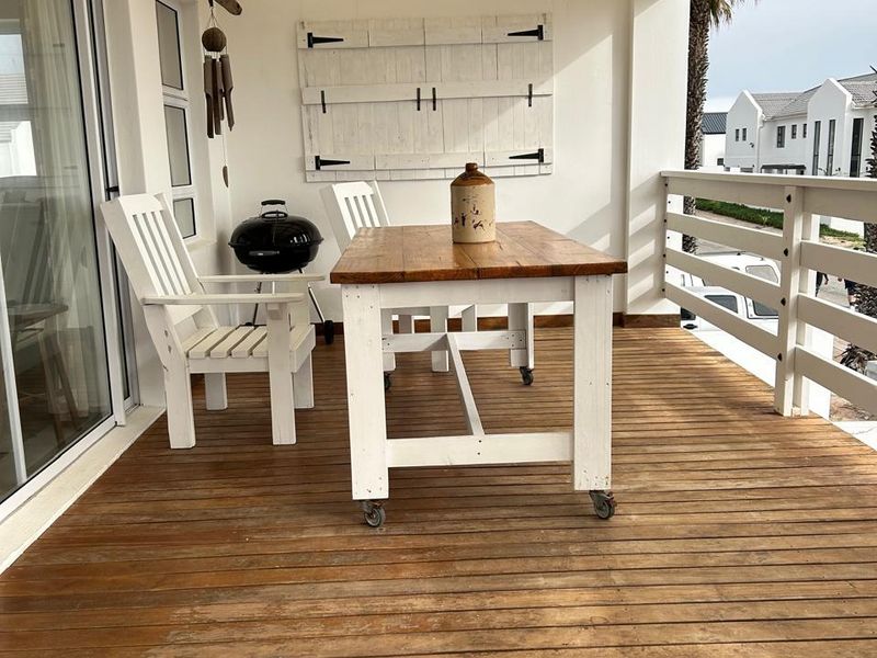 Covered balcony featuring timber decking, a slatted pergola roof, and a timber balustrade, providing an outdoor entertainment space with sliding door access.
