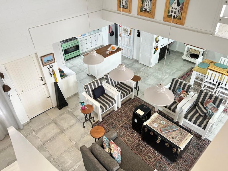 Spacious open-plan living and kitchen area featuring tiled flooring, modern pendant lighting, and a functional kitchen layout with a central island.