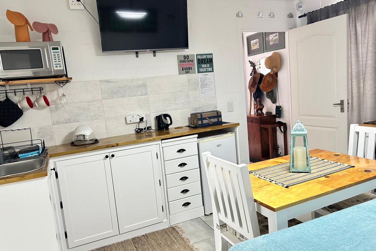 Compact kitchen area featuring white cabinetry, wooden countertops, tiled backsplash, and integrated sink, providing a functional space for meal preparation.