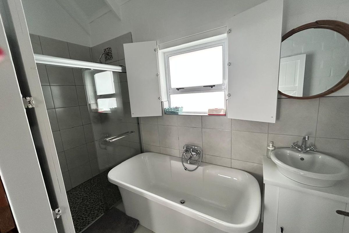 A modern bathroom featuring a freestanding bathtub, a separate glass-enclosed shower with pebble flooring, and a vanity basin.